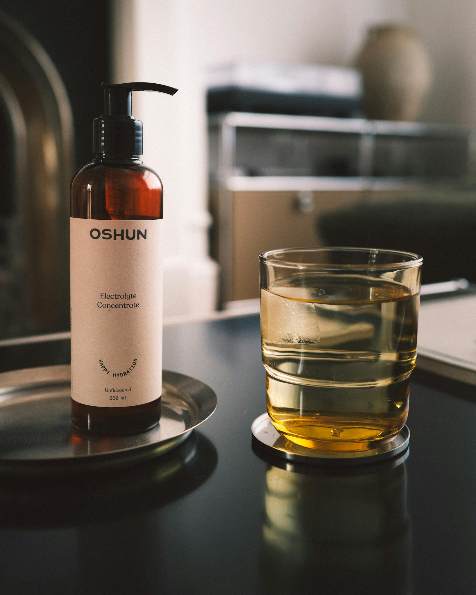 Elegantly styled electrolyte concentrate bottle with a glass on a modern table, indoors.
