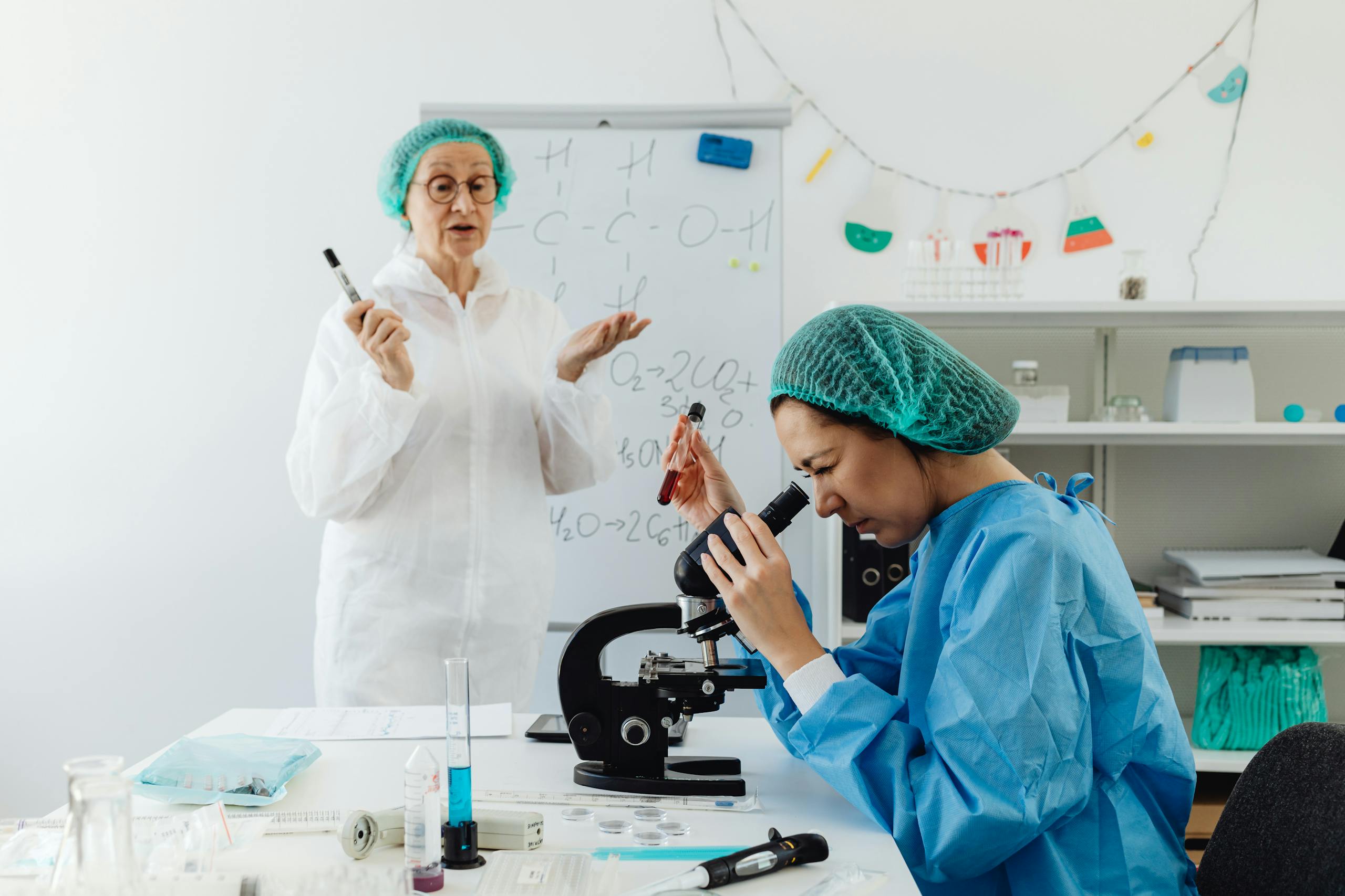 Two female scientists conducting research with microscope in a laboratory setting.